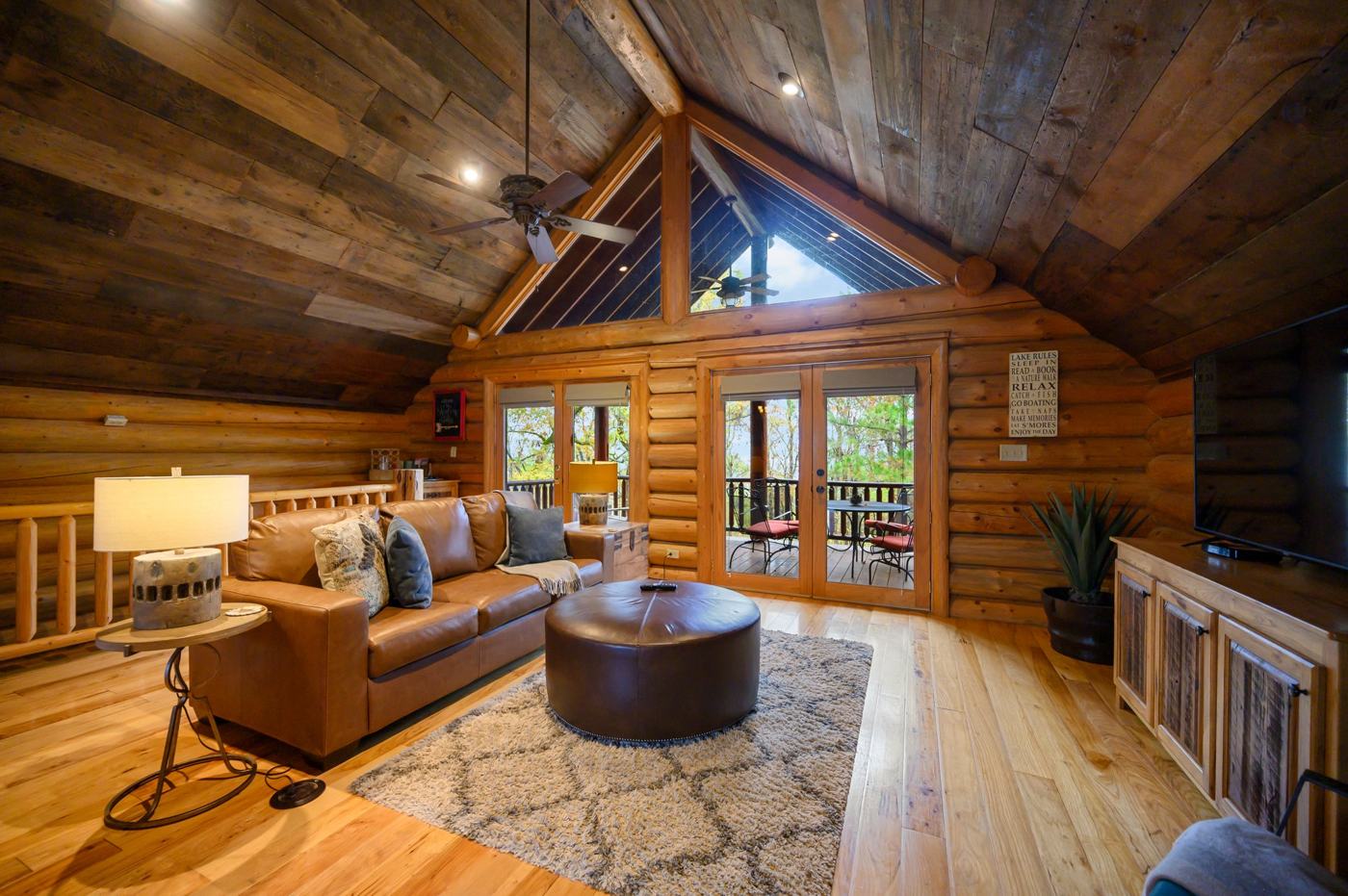 Vaulted log great room with leather sofa and deck doors