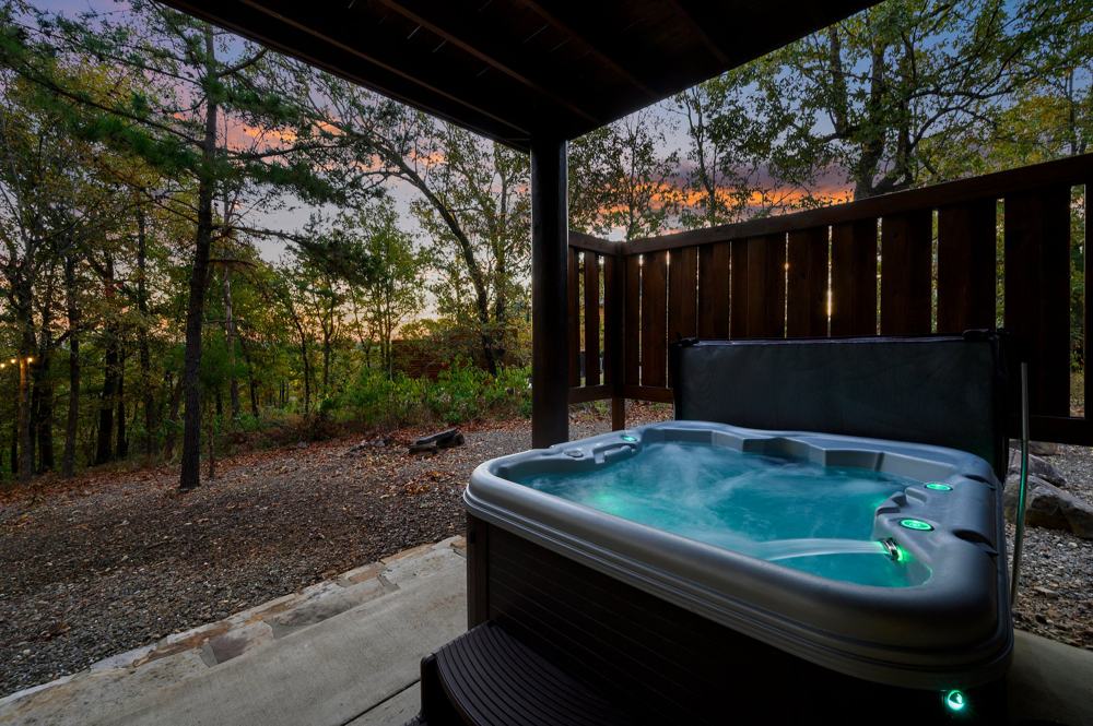 Private hot tub on the guest cabin's covered patio at dusk