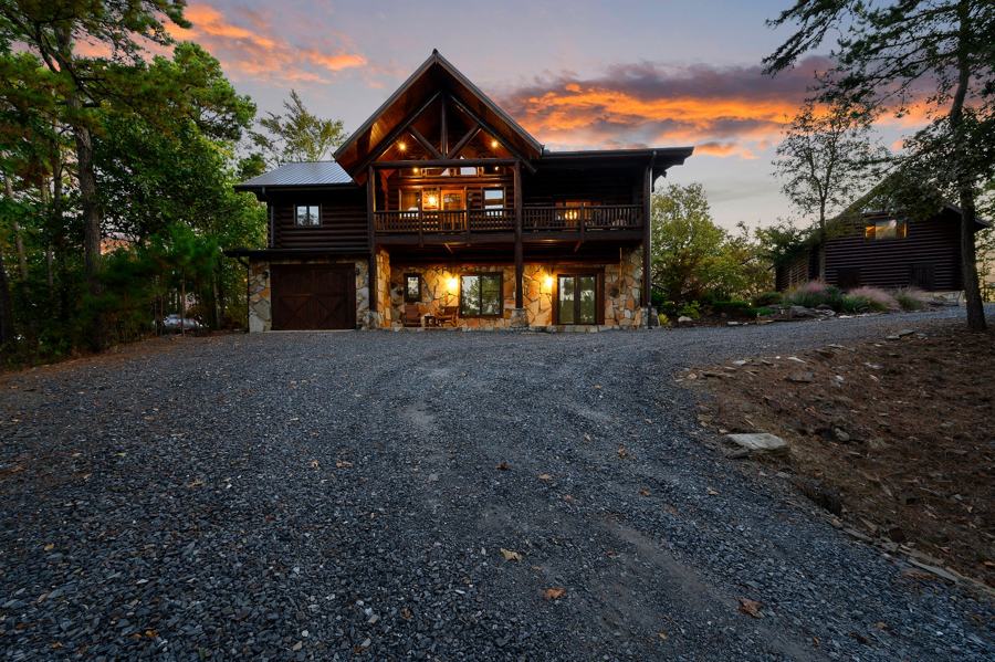 Main lodge glowing at dusk at the end of the gravel drive