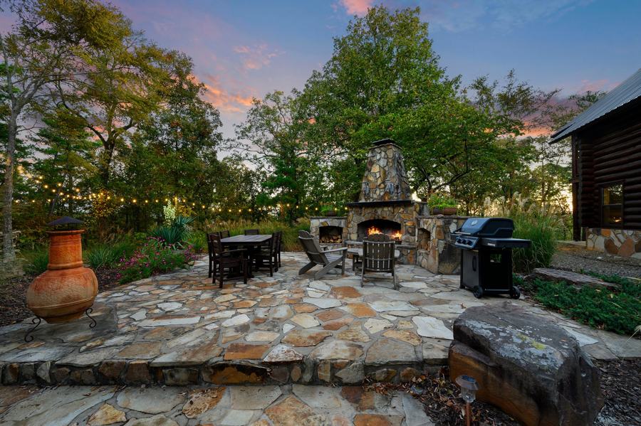 Stone patio with outdoor fireplace, dining table and grill